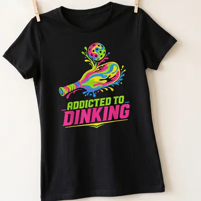 Colorful t-shirt featuring 'Addicted To Dinking' with a pickleball paddle and ball illustration. — printed on a women's shirt