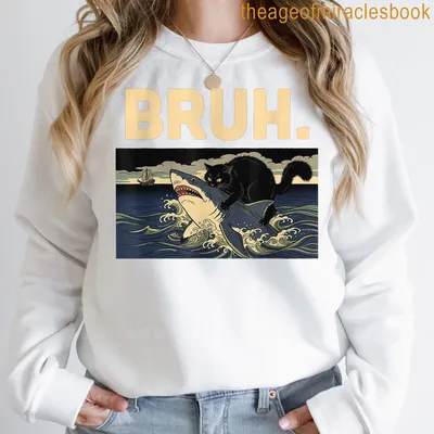 Illustration of a black cat riding a shark with the word BRUH above in bold text — printed on a sweatshirt