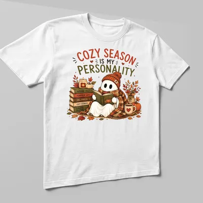 Whimsical illustration of a cute ghost reading with cozy season text — printed on a unisex t-shirt (angled view)