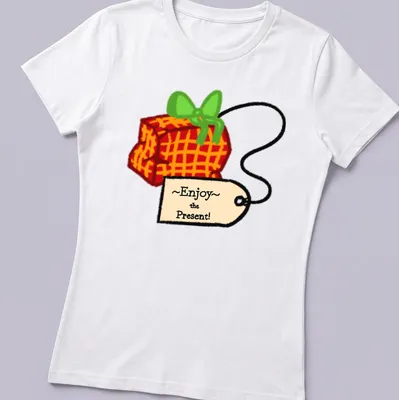 Playful cartoon gift box with colorful accents and the phrase ~Enjoy~ the Present! — printed on a women's shirt