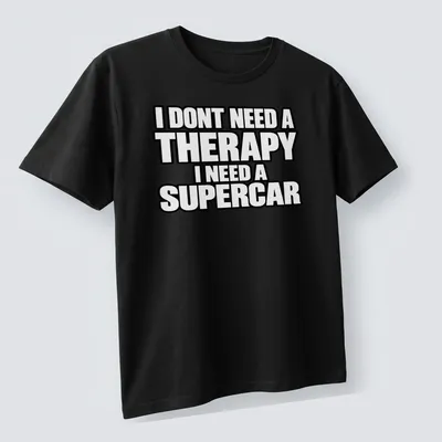 Bold typography t-shirt with the text I DONT NEED A THERAPY I NEED A SUPERCAR on a black background — printed on a unisex t-shirt (angled view)