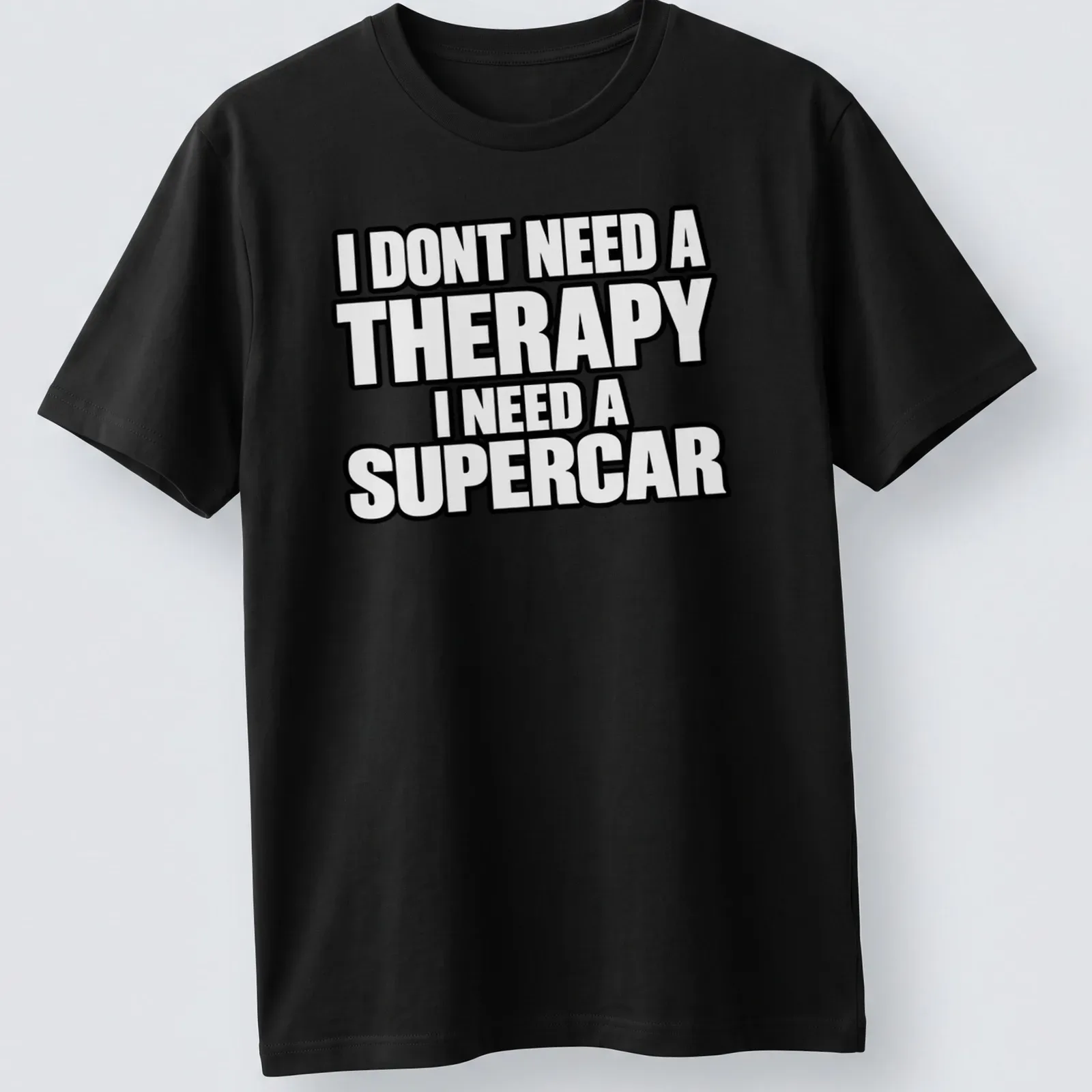 Bold typography t-shirt with the text I DONT NEED A THERAPY I NEED A SUPERCAR on a black background — printed on a unisex t-shirt