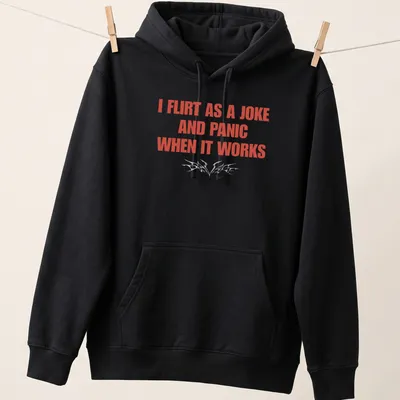 Bold typography shirt reading I Flirt As A Joke And Panic When It Works — printed on a unisex hoodie