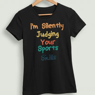 Colorful typography shirt with playful text about judging sports skills — printed on a women's shirt