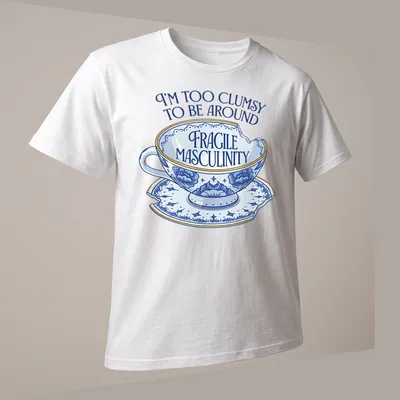 Whimsical illustration of a broken teacup with humorous text about masculinity — printed on a unisex t-shirt (angled view)