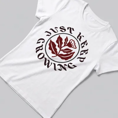 Floral design with leaves and text 'JUST KEEP GROWING' in dark red, green, and white — printed on a women's shirt