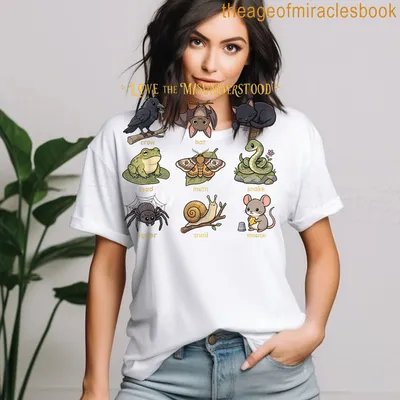 Kawaii cartoon t-shirt featuring a cat, bat, frog, and spider with colorful text. — printed on a women's t-shirt