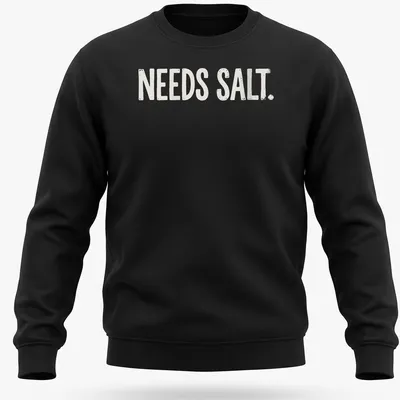 Bold distressed chef graphic with the text 'NEEDS SALT.' in white and light beige — printed on a unisex sweatshirt