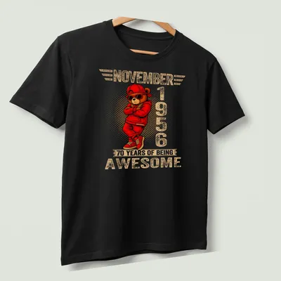 Cartoon teddy bear with colorful text celebrating 70 years of being awesome — printed on a unisex t-shirt (angled view)