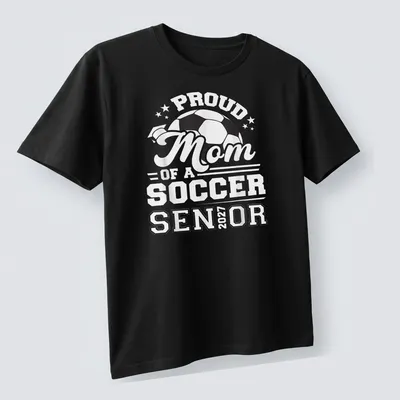 Bold typography celebrating Proud Mom of a Soccer Senior 2027 with a soccer ball — printed on a unisex t-shirt (angled view)