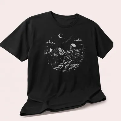 Vintage illustration of a skeleton hiker enjoying a mountain view in shades of gray and green. — printed on a unisex t-shirt (angled view)