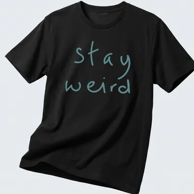 Playful handwritten text 'stay weird' in teal on a t-shirt.