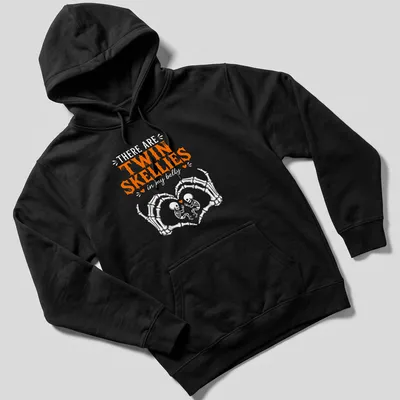 Playful Halloween shirt with twin skeletons and fun text in orange and white — printed on a unisex hoodie