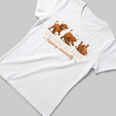 Cartoon Highland cow with the text 'WALKING BY FAITH tripping constantly' in playful colors — printed on a women's shirt