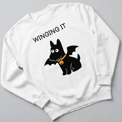 Cartoon Scottish Terrier with bat wings and the text WINGING IT in orange and black — printed on a unisex sweatshirt