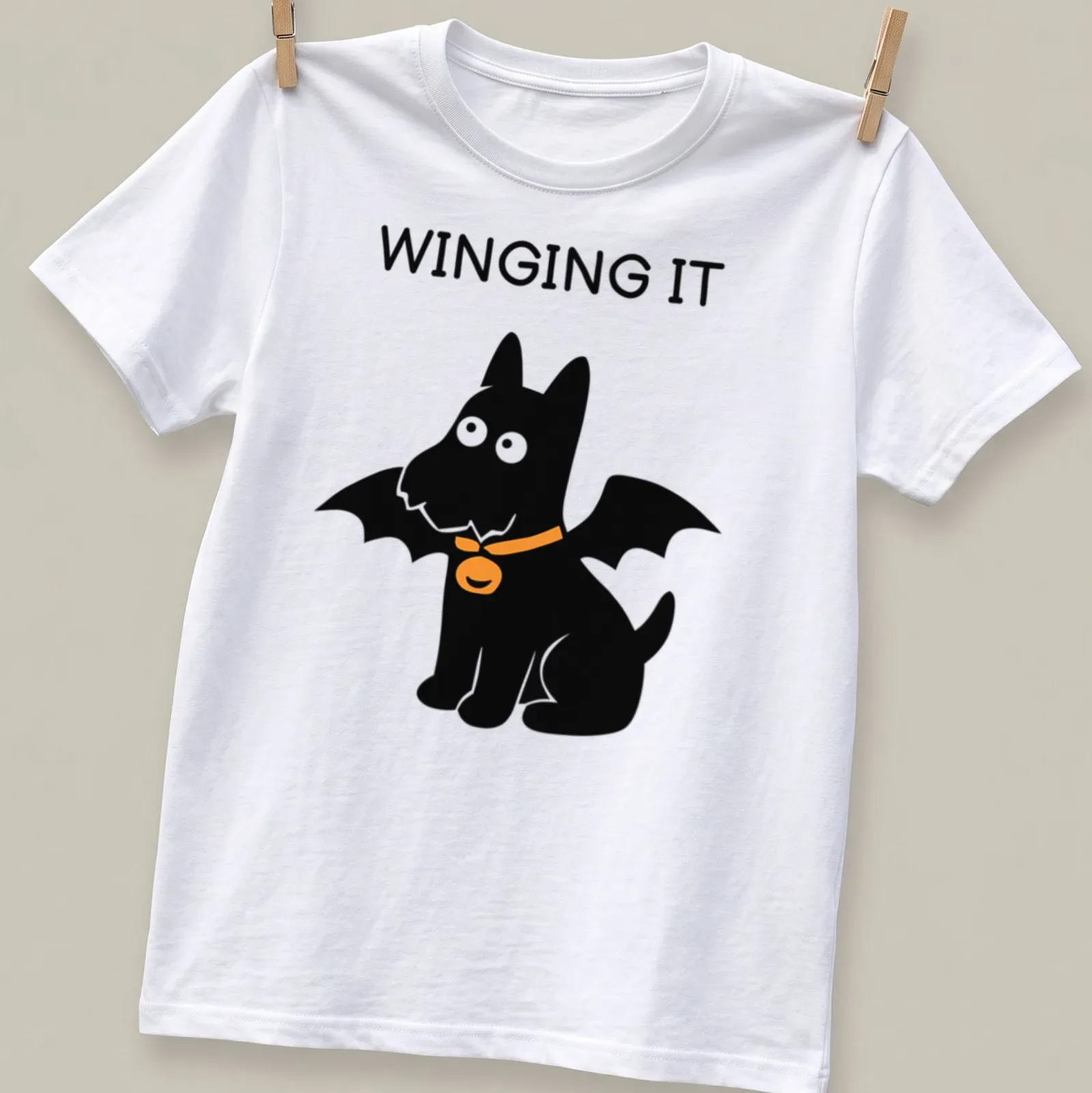 Cartoon Scottish Terrier with bat wings and the text WINGING IT in orange and black — printed on a unisex t-shirt